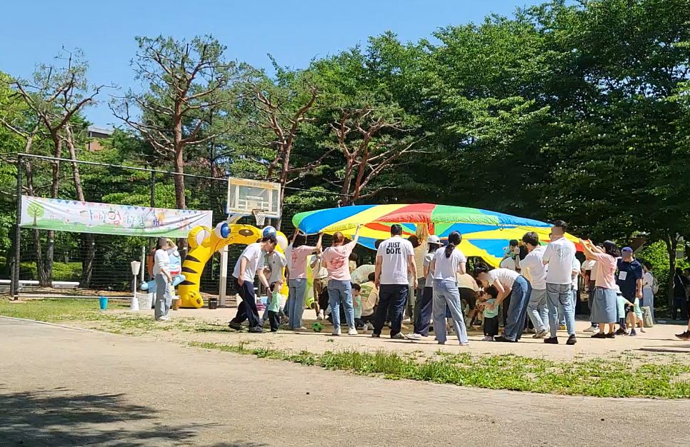 야외에서 대형 낙하산 천을 들고 노는 가족들