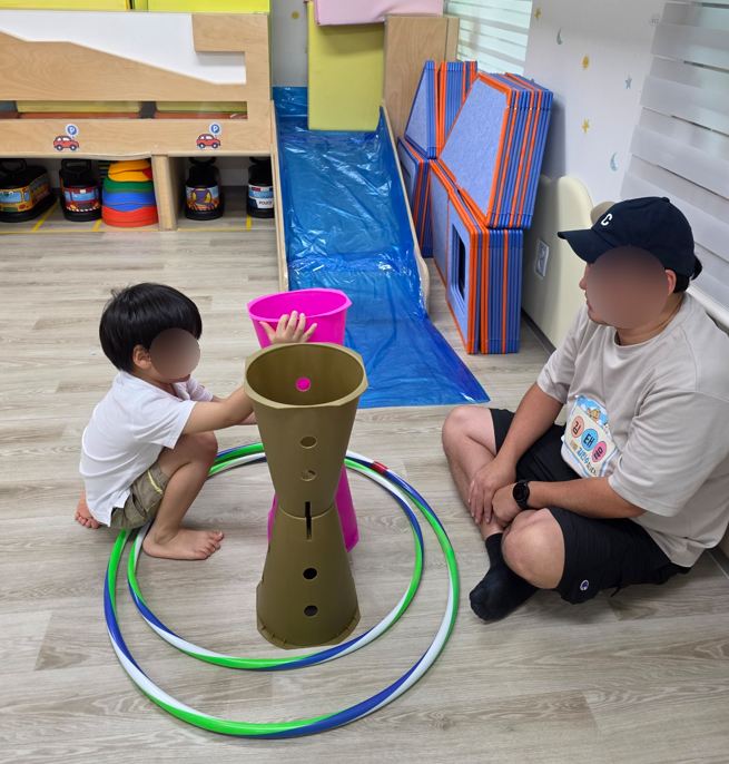 아빠와 아이가 훌라후프와 교구로 함께 노는 모습